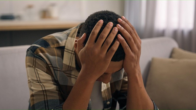 Mwanaume ameshika kichwa kwa huzuni, akionyesha hasara au matatizo.