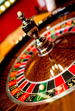 Picha ya karibu ya gurudumu la roulette lenye mpira mdogo na namba za rangi nyekundu, nyeusi na kijani.