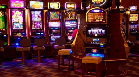 Mashine za slot zenye mwanga mkali zimepangwa ndani ya ukumbi wa kasino.