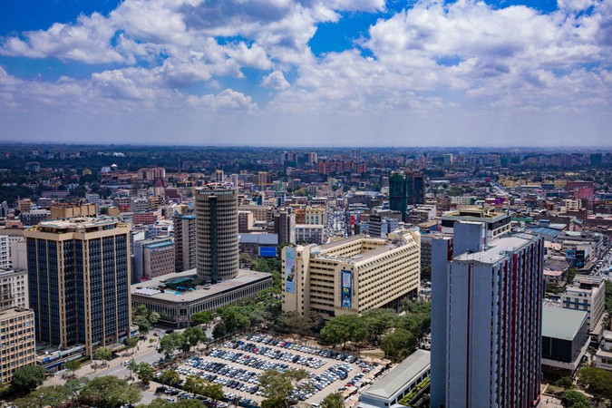 Mandhari ya juu ya majengo mengi katika jiji kubwa la Afrika chini ya anga lenye mawingu meupe.