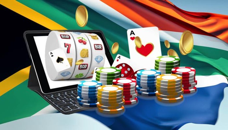 Picha inaonyesha kompyuta kibao yenye mashine ya sloti, kadi za mchezo na sarafu mbele ya bendera ya Afrika Kusini, ikiwakilisha casino mtandaoni.