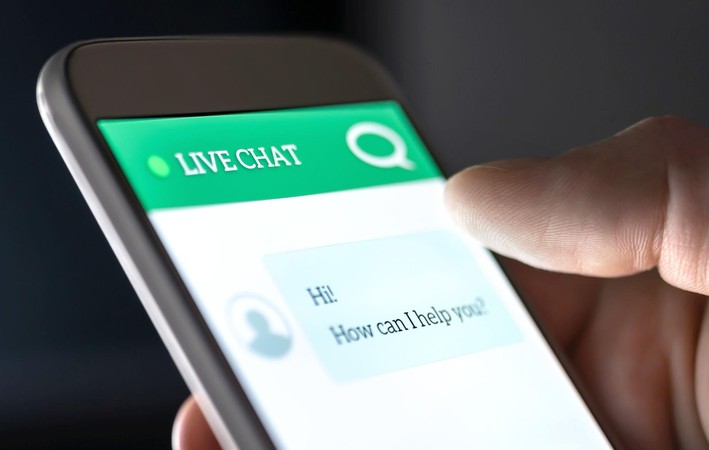 Kidole kinagusa skrini ya simu yenye sehemu ya live chat, ikionyesha huduma ya msaada kwa wateja kwenye simu.