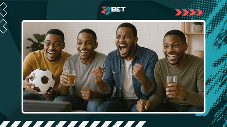 Wanaume wanne wenye furaha wameketi pamoja wakitazama mchezo wa mpira na kushangilia mbele ya bango la 22BET.