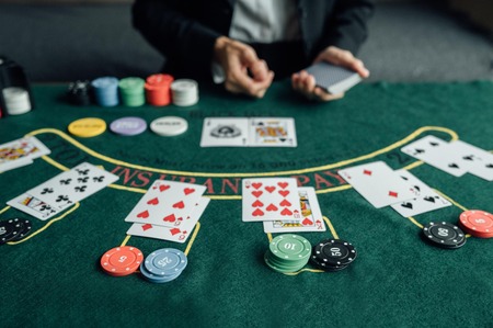Meza ya blackjack yenye kadi, chips na dealer akiwa anagawa mchezo wa kasino.