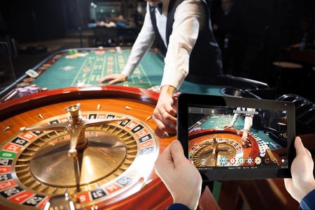 Tableti inaonyesha roulette ya moja kwa moja mbele ya meza halisi ya roulette kwenye kasino.